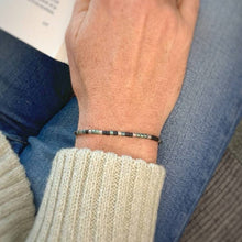 Load image into Gallery viewer, Mens 'Stay Strong' Morse Code Bracelet being worn, with book in the background