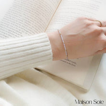 Load image into Gallery viewer, 'Stay Strong' Morse Code Bead Bracelet being worn with book in background