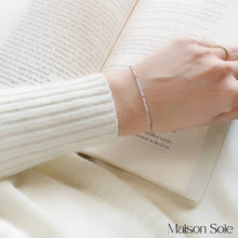 Load image into Gallery viewer, &#39;Grandma&#39; Morse Code Bead Bracelet being worn, with book in background
